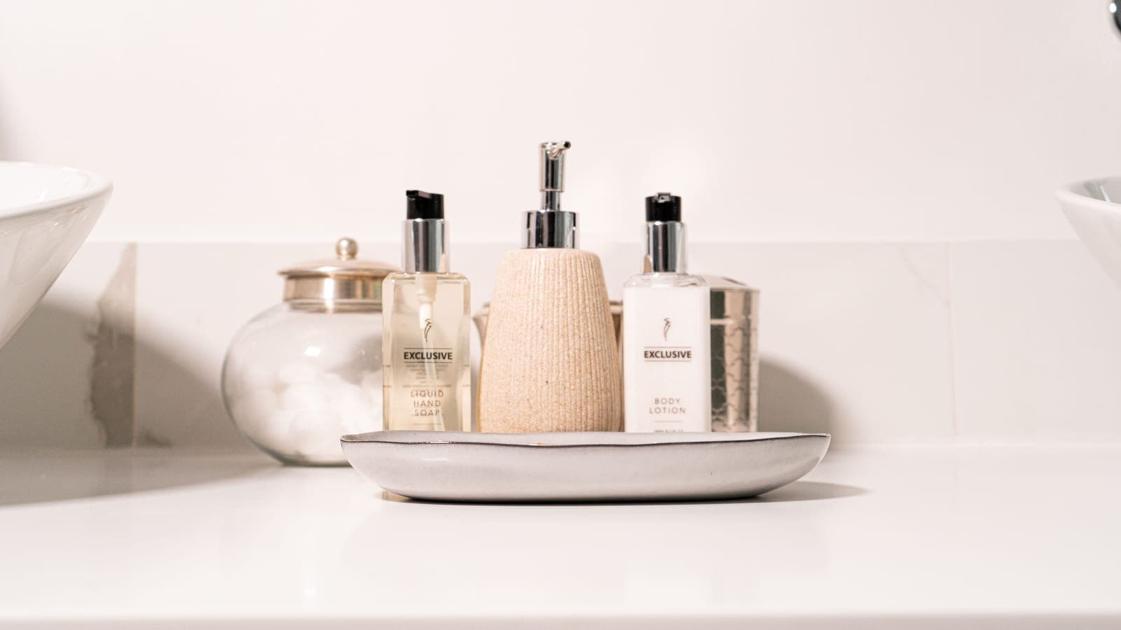 A minimalist bathroom sink with hand soap and lotion in soft daylight