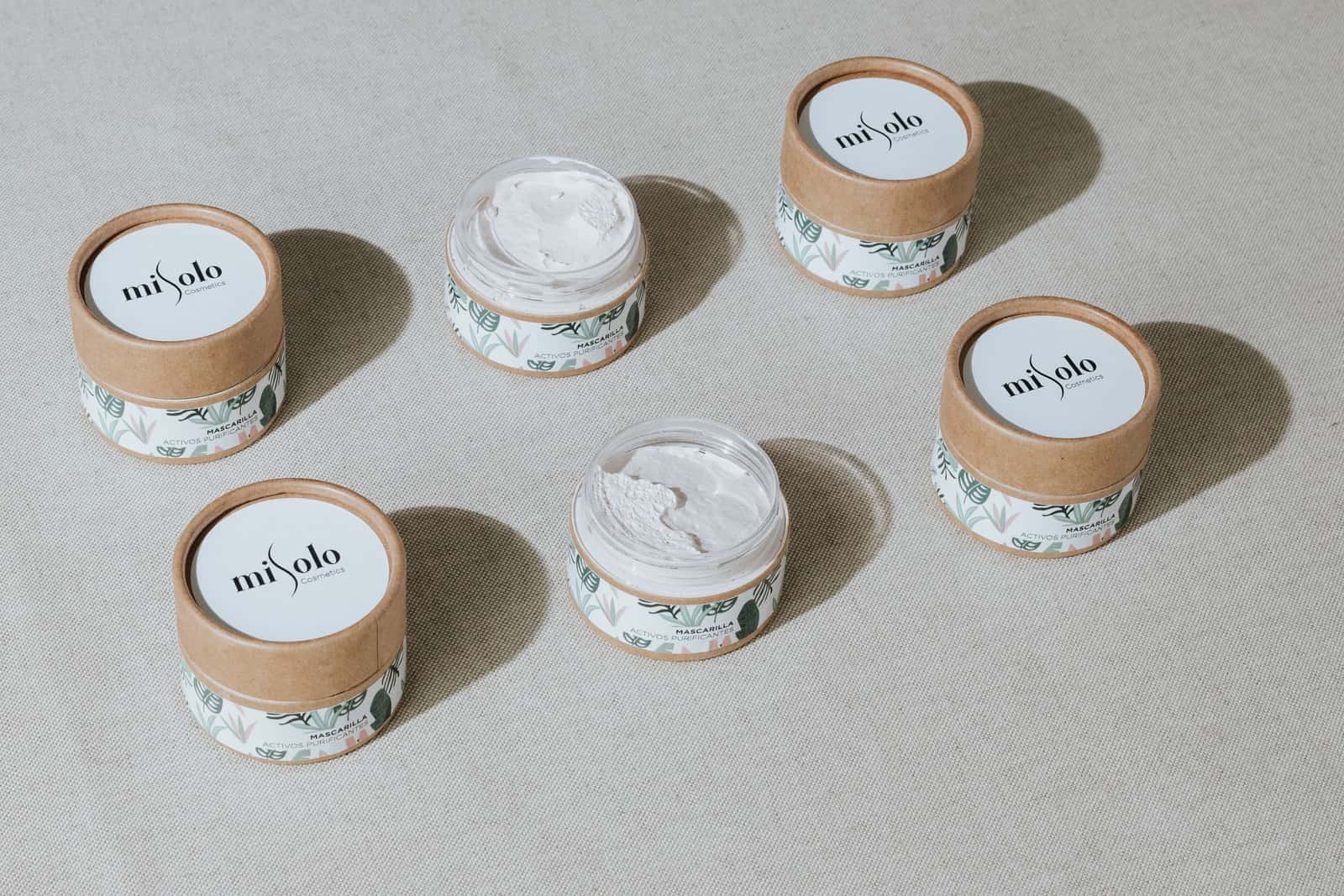 Minimalist skincare jars with cream on a textured linen background