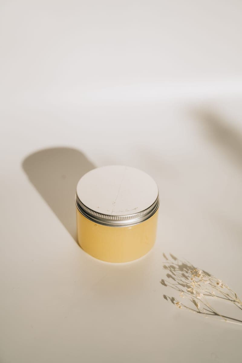 A minimalist skincare container on a white surface with soft shadows