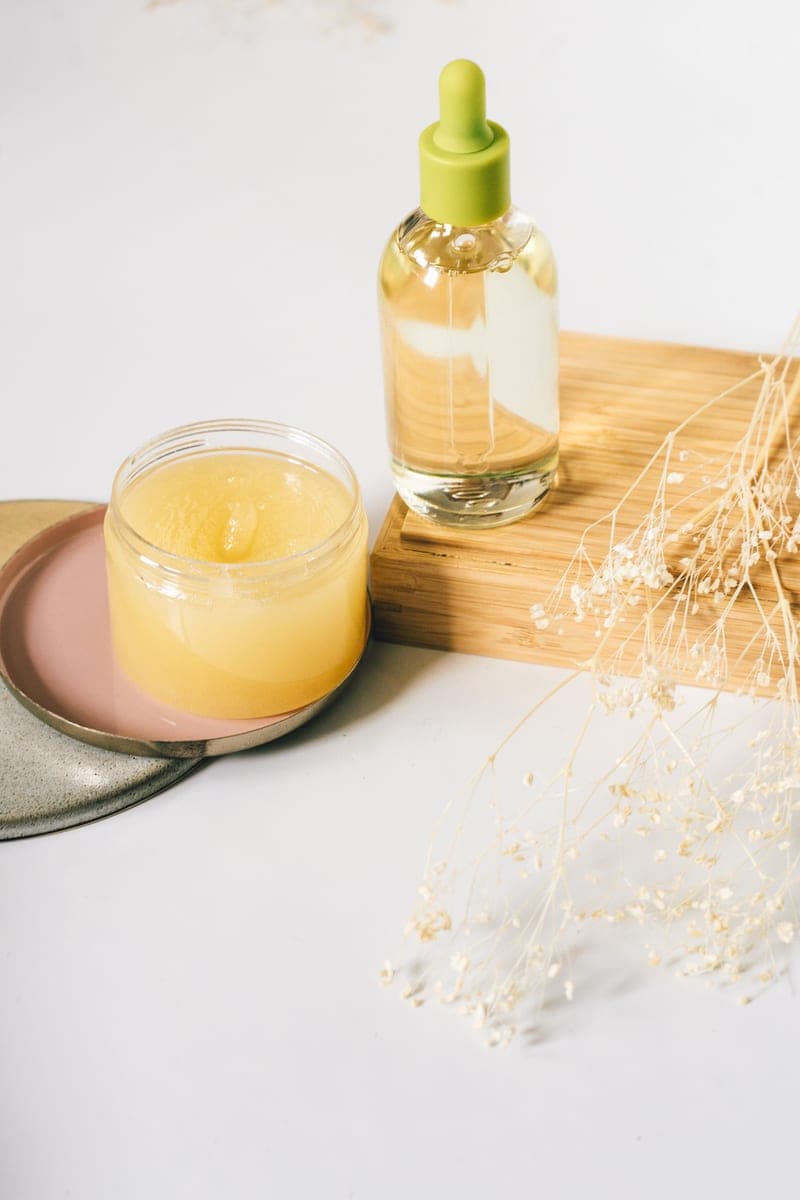 Skincare oil and balm with dried flowers on a wooden surface