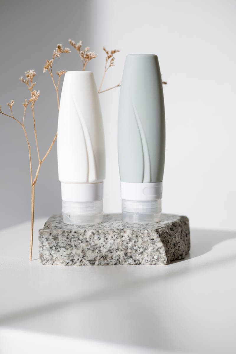 Two plain cosmetic tubes on a stone surface in natural light