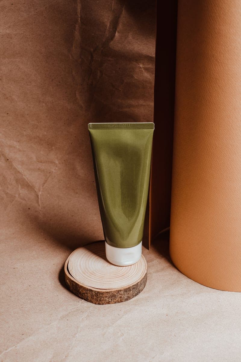 A plain cosmetic tube standing upright on a wooden stand