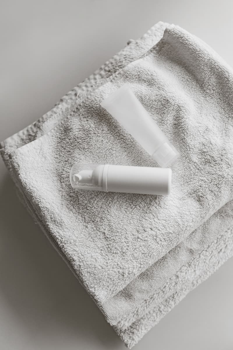 Skincare bottles resting on a soft white towel