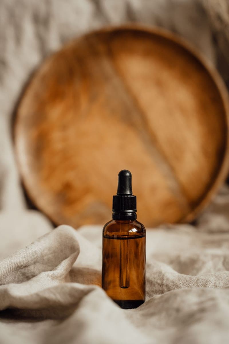 An amber glass dropper bottle against a rustic wooden backdrop