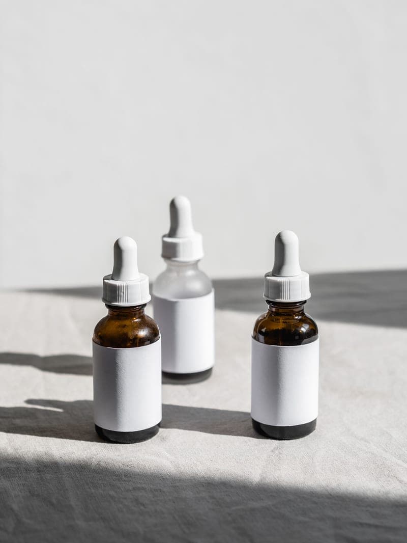 Three serum bottles with droppers on a fabric surface in natural light