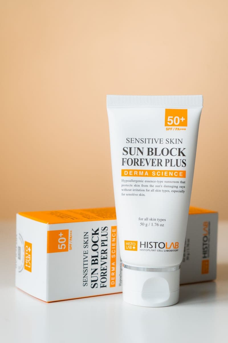 A high-SPF sunblock bottle for sensitive skin on a neutral background