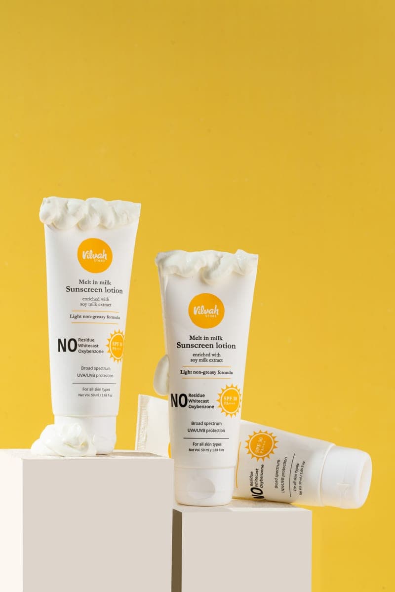 Sunscreen tubes displayed on pale blocks against a warm background